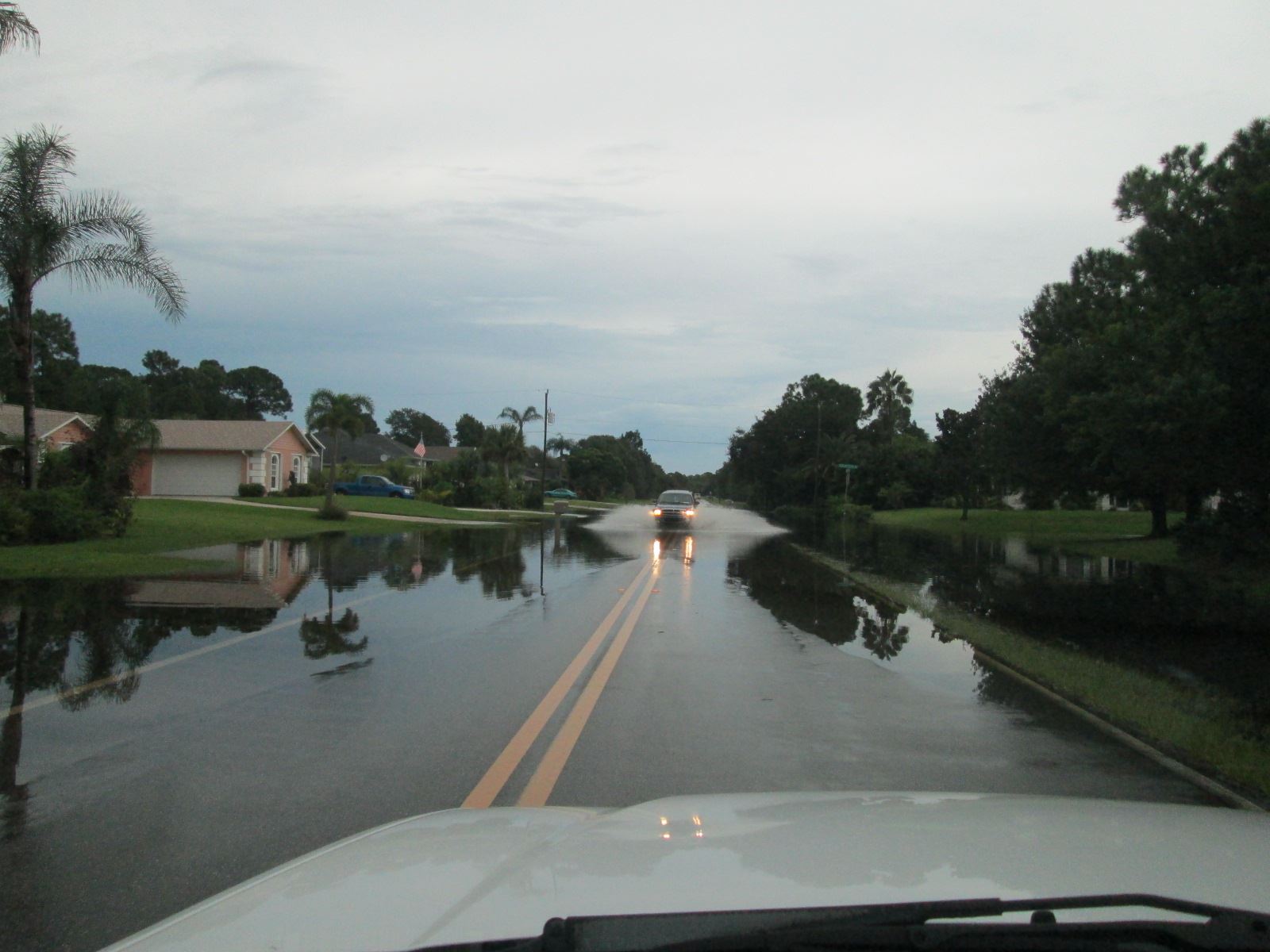 Person Driving Car Through Street in Water